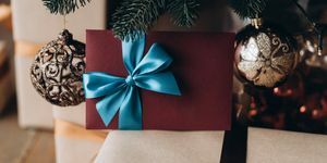 gavekort i bordeaux konvolut med blå sløjfe under juletræet julegave
